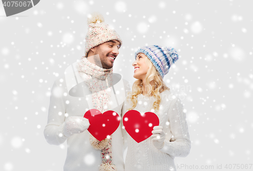 Image of smiling couple in winter clothes with red hearts