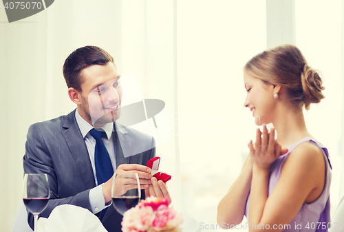 Image of man proposing to his girlfriend at restaurant