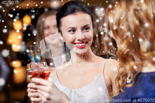 Image of happy women with drinks at night club over snow