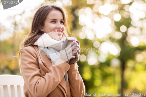 Image of happy young woman drinking coffee in autumn park