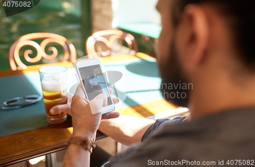 Image of close up of man with smartphone and beer at pub