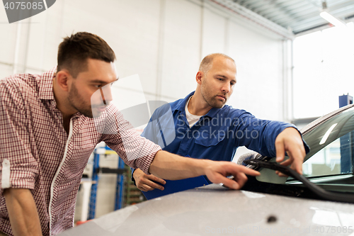 Image of auto mechanic with clipboard and man at car shop