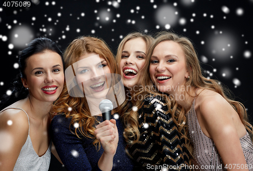 Image of happy young women with microphone singing karaoke