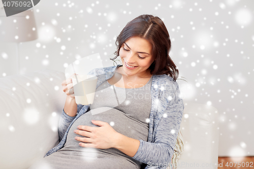 Image of happy pregnant woman with cup drinking tea at home