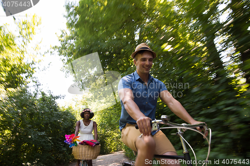 Image of Young multiethnic couple having a bike ride in nature