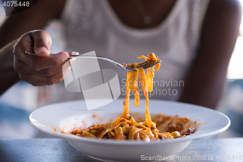 Image of a young African American woman eating pasta