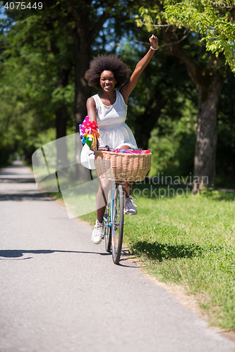 Image of pretty young african american woman riding a bike in forest