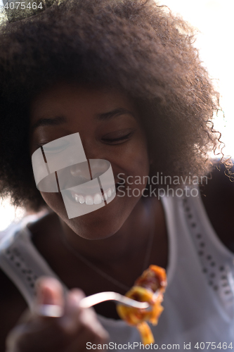 Image of a young African American woman eating pasta