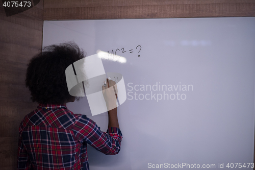 Image of African American woman writing on a chalkboard in a modern offic