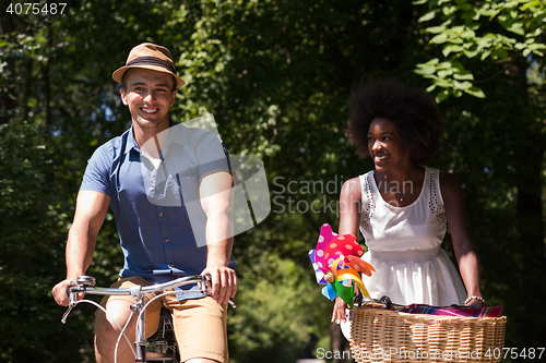 Image of Young multiethnic couple having a bike ride in nature