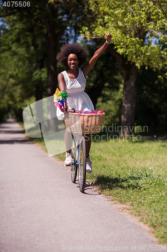Image of pretty young african american woman riding a bike in forest