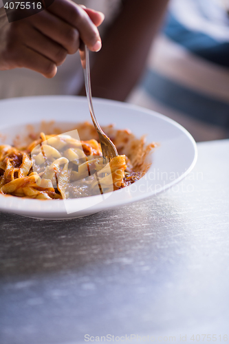 Image of a young African American woman eating pasta