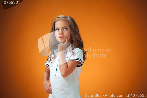 Image of The cute thoughtful little girl on orange background