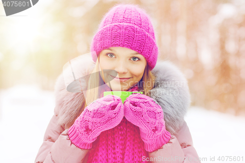 Image of smiling young woman with cup in winter forest