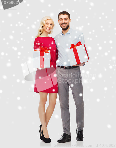 Image of happy couple with christmas gift boxes over snow