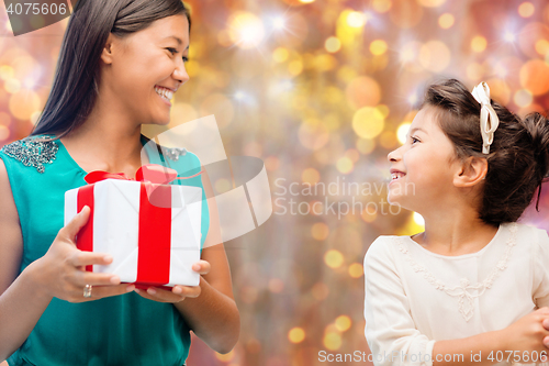 Image of happy mother and girl with gift box over lights