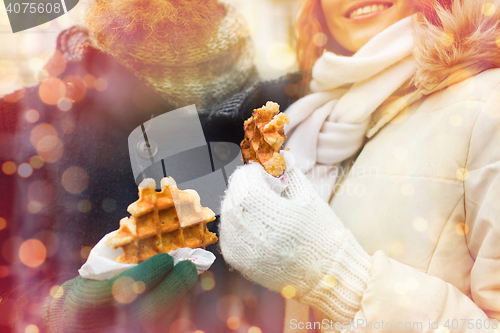 Image of close up of happy couple eating waffles outdoors