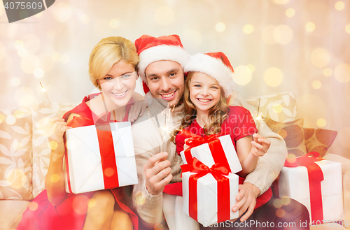 Image of smiling family holding gift boxes and sparkles