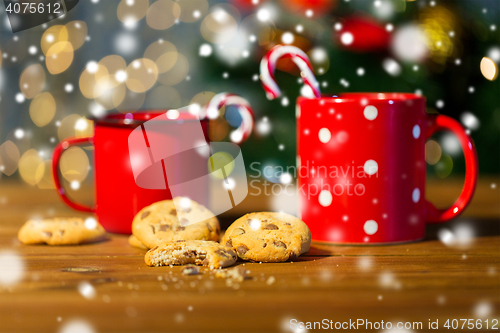 Image of christmas candy canes and cups on wooden table