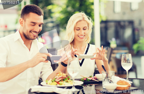 Image of happy couple with smatphone photographing food