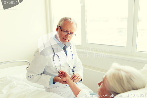 Image of doctor checking senior woman pulse at hospital