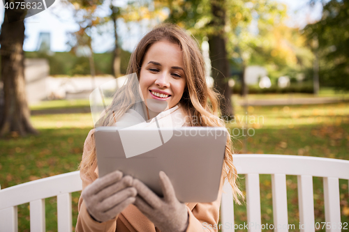 Image of happy young woman with tablet pc in autumn park