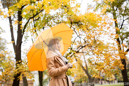 Image of happy woman with umbrella walking in autumn park