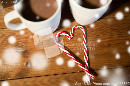 Image of christmas candy canes and cups on wooden table