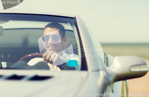 Image of happy man driving cabriolet car outdoors