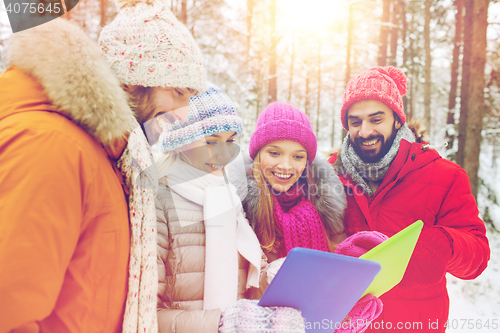 Image of smiling friends with tablet pc in winter forest