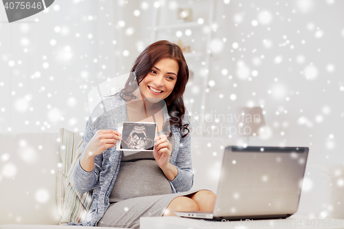 Image of pregnant woman with ultrasound image and laptop