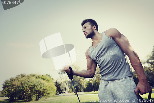 Image of young man exercising with expander in summer park