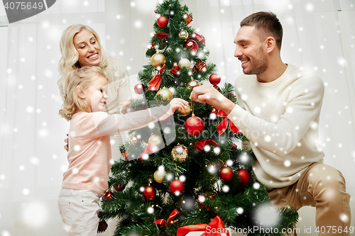 Image of happy family decorating christmas tree at home