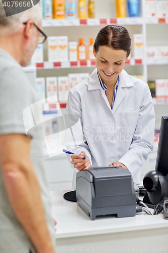 Image of pharmacist writing check for customer at drugstore