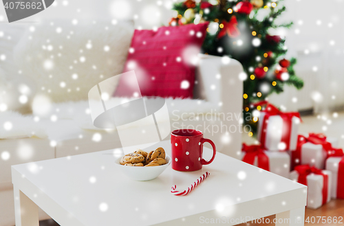 Image of close up of christmas cookies, sugar cane and cup