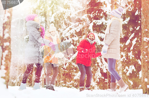 Image of group of happy friends playing snowballs in forest