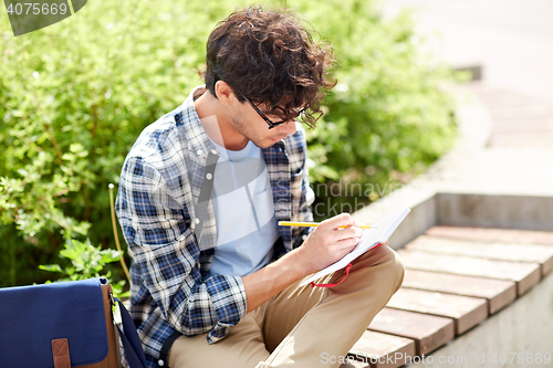 Image of man with notebook or diary writing on city street