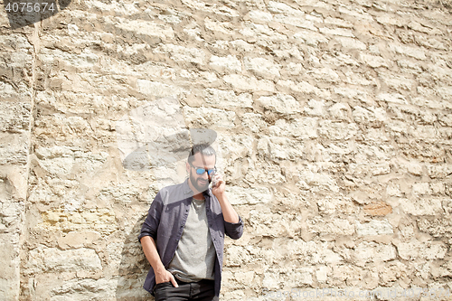 Image of smiling man with smartphone calling on city street