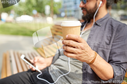 Image of man with earphones and smartphone drinking coffee