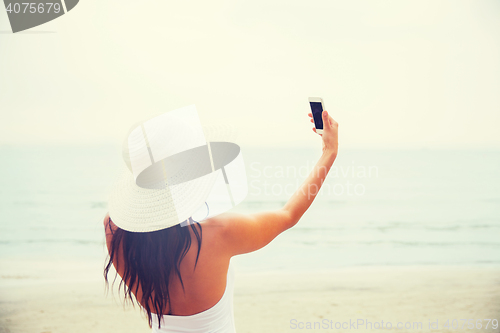 Image of smiling young woman taking selfie with smartphone