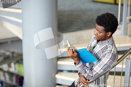 Image of african student boy or man reading book at library