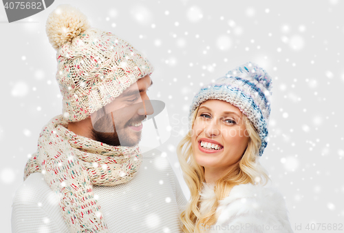 Image of smiling couple in winter clothes hugging over snow