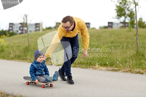 Image of happy father and little son riding on skateboard