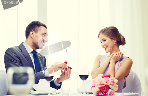 Image of man proposing to his girlfriend at restaurant