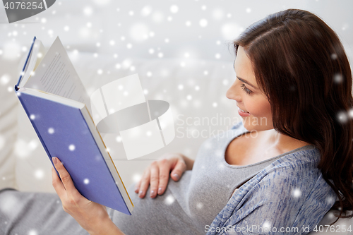 Image of happy pregnant woman reading book at home