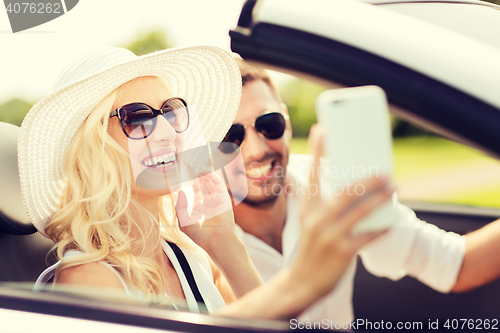 Image of happy couple in car taking selfie with smartphone