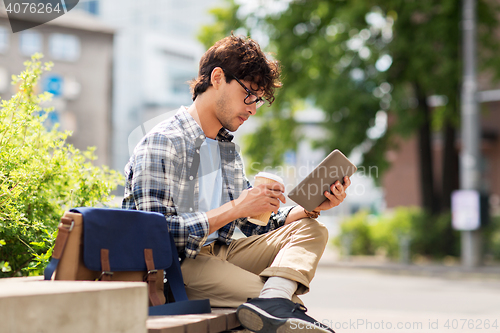 Image of man with tablet pc sitting on city street bench