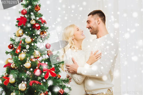 Image of happy couple hugging near christmas tree at home
