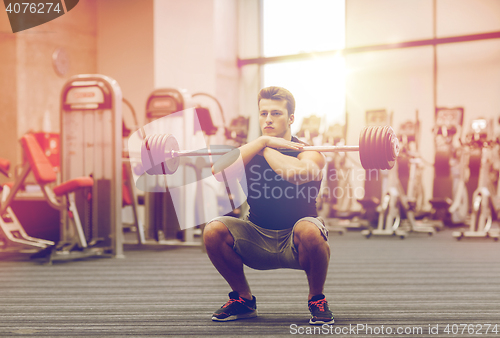 Image of young man flexing muscles with barbell in gym