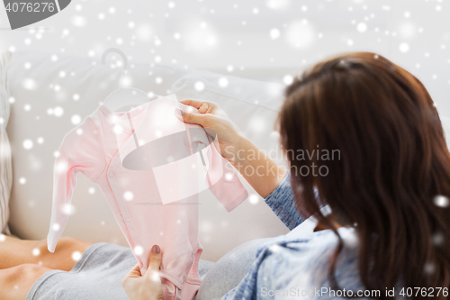 Image of close up of happy woman with baby bodysuit at home